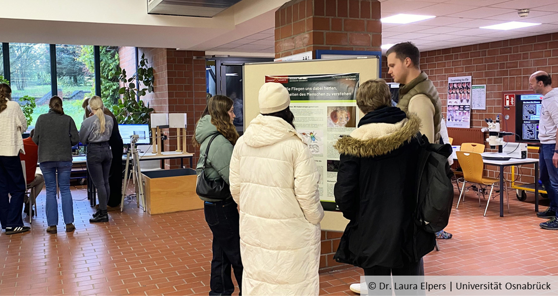 Pupils stand in the foyer of the biology building, with hands-on stands in the background.