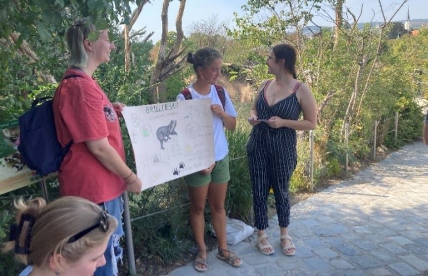 Zwei Personen stehen im Zoo und halten ein Plakat.